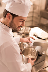 Wall Mural - side view of confectioner cooking dessert in restaurant kitchen