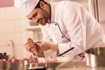 Wall Mural -  confectioner decorating cupcakes with cream in restaurant kitchen