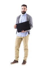 Poster - Happy smiling successful businessman opening laptop and looking at camera. Full body length portrait isolated on white studio background. 