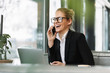 Smiling blonde business woman talking by mobile phone