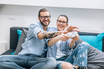 Wall Mural - Young couple playing video games at home.