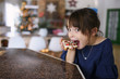 © RooM The Agency - Mischievous girl sitting at a table eating a homemade Christmas tree cookie