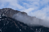 Fototapeta Na ścianę - Clouds hitting a vertical stone wall in the Austrian Alps