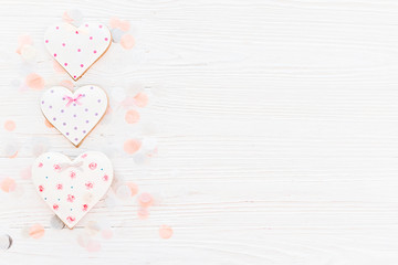 Wall Mural - pink cookie hearts on white rustic wooden background with confetti in soft light. happy mother's day greeting card. space for text . happy valentine's day or women's. mock-up