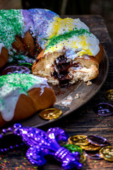 Wall Mural - king cake with slice cut out showing chocolate pudding filling surrounded by mardi gras decorations