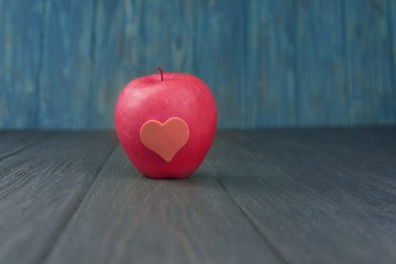 Wall Mural - ripe red apple with heart on a wooden background on holiday in february valentine's day