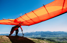 Man With Hang-glider Starting To Fly From The Hill Top