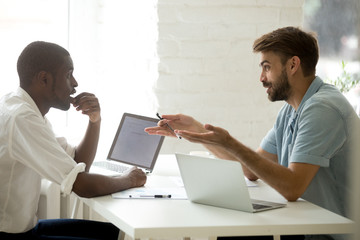 Canvas Print - Multi-ethnic partners coworking in office teamwork, african american and caucasian businessmen share interesting ideas project plans at workplace, friendly white mentor teaching black intern at work