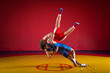 © Виталий Сова - Two greco-roman  wrestlers in red and blue uniform wrestling  on a yellow wrestling carpet in the gym