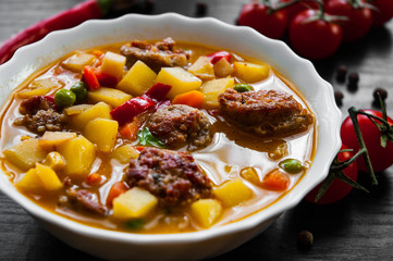 Wall Mural - Bowl of sausage soup with mix vegetables on a dark wooden background