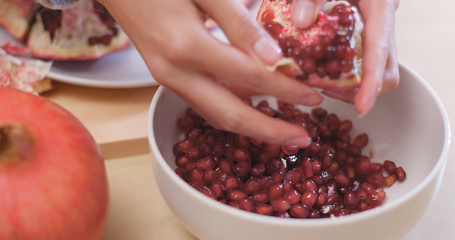 Wall Mural -  Putting Fresh red pomegranate into bowl