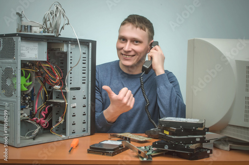 Happy Cheerful Computer Technician Engineer Of User Support Service Is Holding In Hands A Phone And Is Showing On Broken Pc Buy This Stock Photo And Explore Similar Images At Adobe