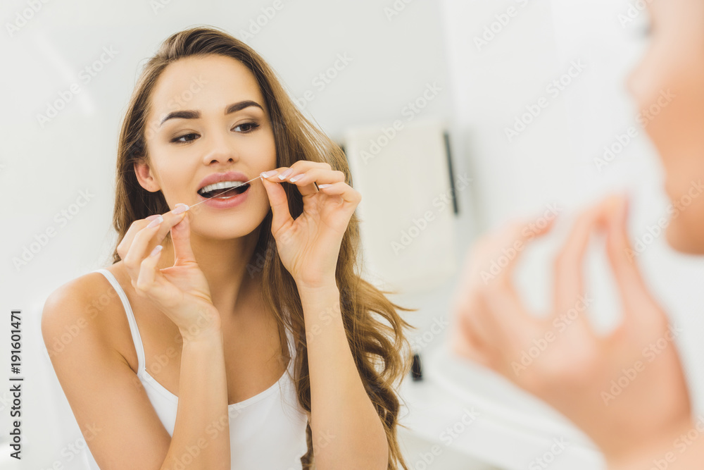 portrait of beautiful woman cleaning teeth with dental floss - obrazy, fototapety, plakaty 