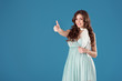 © LIGHTFIELD STUDIOS - smiling girl in blue dress showing thumb up isolated on blue