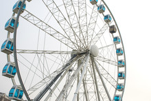 Detail Of A Large And High Ferris Wheel With Poles And White Irons. The Cabins Have Blue Glass And There Is None.