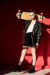 © LIGHTFIELD STUDIOS - beautiful stylish girl in black leather jacket posing with longboard, on red