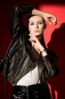 © LIGHTFIELD STUDIOS - stylish young woman posing in black leather jacket for fashion shoot on red