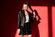 © LIGHTFIELD STUDIOS - beautiful girl with ponytail hairstyle posing in black leather jacket for fashion shoot on red