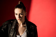 © LIGHTFIELD STUDIOS - portrait of attractive young woman posing in black leather jacket for fashion shoot on red