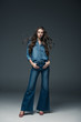 © LIGHTFIELD STUDIOS - fashionable young woman girl with long hair posing in flare jeans, on grey