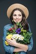 © LIGHTFIELD STUDIOS - beautiful cheerful girl in straw hat holding flowers for international womens day, isolated on grey