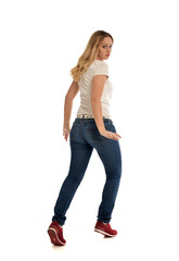 Canvas Print - full length portrait of blonde girl wearing simple white shirt and jeans, standing pose, isolated on white studio background.