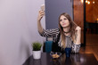 © Надежда Манахова - A beautiful young woman is making a selfie in a cafe, beside is a cookie and a cup with coffee or tea. Slavic appearance, life style. Copy space.