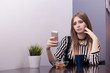 © Надежда Манахова - A beautiful young woman sits at a table with a mug of tea and a biscuit with a very sad and sad face and holds in her hand a phone, a rustle, resentment, a bad mood. Internet trolling.