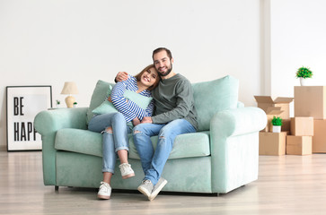 Poster - Young couple sitting on sofa after moving to new home