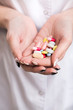 © proimagecontent - Closeup of a woman doctor holding colorful pills in his hands