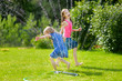 © MNStudio - Adorable little girls playing with a sprinkler in a backyard on sunny summer day. Cute children having fun with water outdoors.