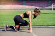 © gorynvd - Ready to go! Female athlete on the starting line of a stadium track, preparing for a run. Fitness girl is preparing to run from a low start. Healthy lifestyle.