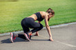 © gorynvd - Ready to go! Female athlete on the starting line of a stadium track, preparing for a run. Fitness girl is preparing to run from a low start. Healthy lifestyle.