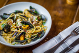 Fototapeta Boho - spaghetti vongole italian seafood pasta dish on white plate  on wooden table