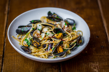 spaghetti vongole close up shot of italian seafood pasta dish on white plate  on wooden table