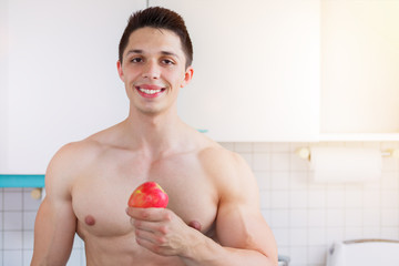 Wall Mural - Gesunde Ernährung junger Bodybuilder Mann Textfreiraum Essen Apfel Frucht Obst in der Küche