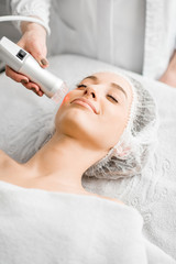 Young woman during a facial massage with professional tool at the medical center