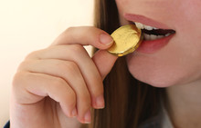 Girl With Long Hair Biting In A Chocolate Gold Coin