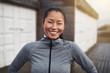 © Flamingo Images - Smiling young Asian woman standing outside before a jog