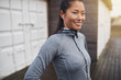 © Flamingo Images - Young Asian woman in sportswear standing outside before a run