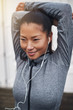 © Flamingo Images - Fit young Asian woman wearing earphones stretching before a run