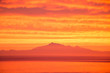 Vibrant orange ocean sunset with mountains