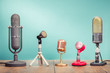 © BrAt82 - Retro old microphones for press conference or interview recording on wooden table front gradient aquamarine wall background. Vintage old style filtered photo