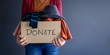 Donation Concept. Woman holding a Donate Box with full of Clothes. standing by the Wall in House