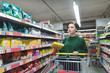 © bodnarphoto - Portrait of a buyer girl with packaging in the middle of a supermarket. A beautiful and positive girl shopping in a supermarket