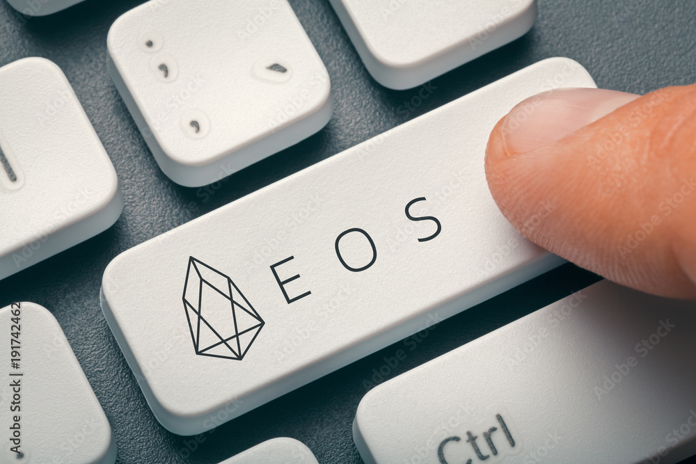 finger pressing computer key with eos coin logo. crypto mining concept