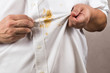 Person pointing to spilled curry stain on white shirt.