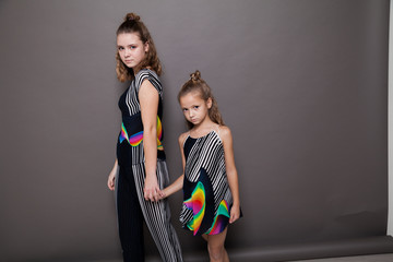 two girls fashionable posing on a grey background