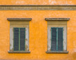 Closed windows in yellow wall with green shutters
