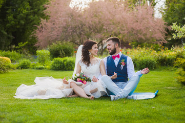 Groom and bride in yoga lotus pose in garden